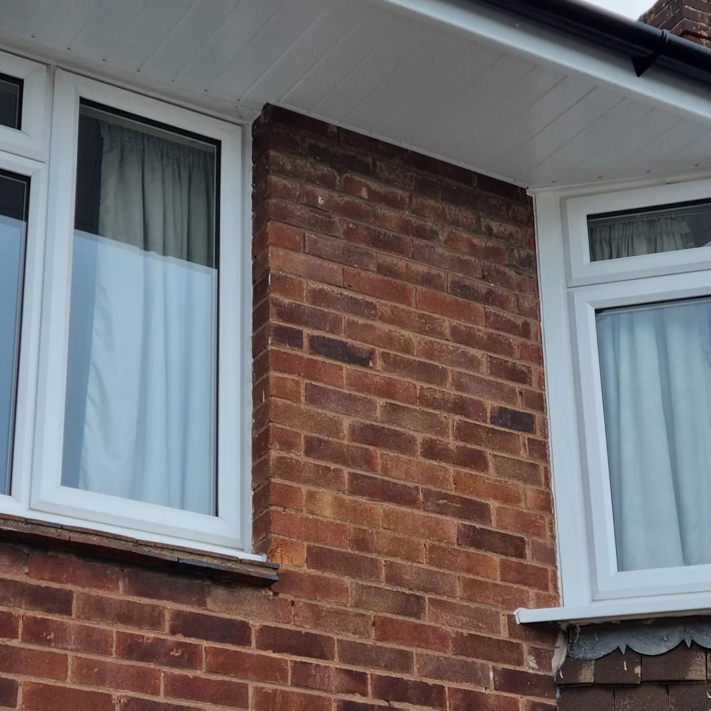 New white uPVC fascia and soffit installation with black guttering on a red-brick house