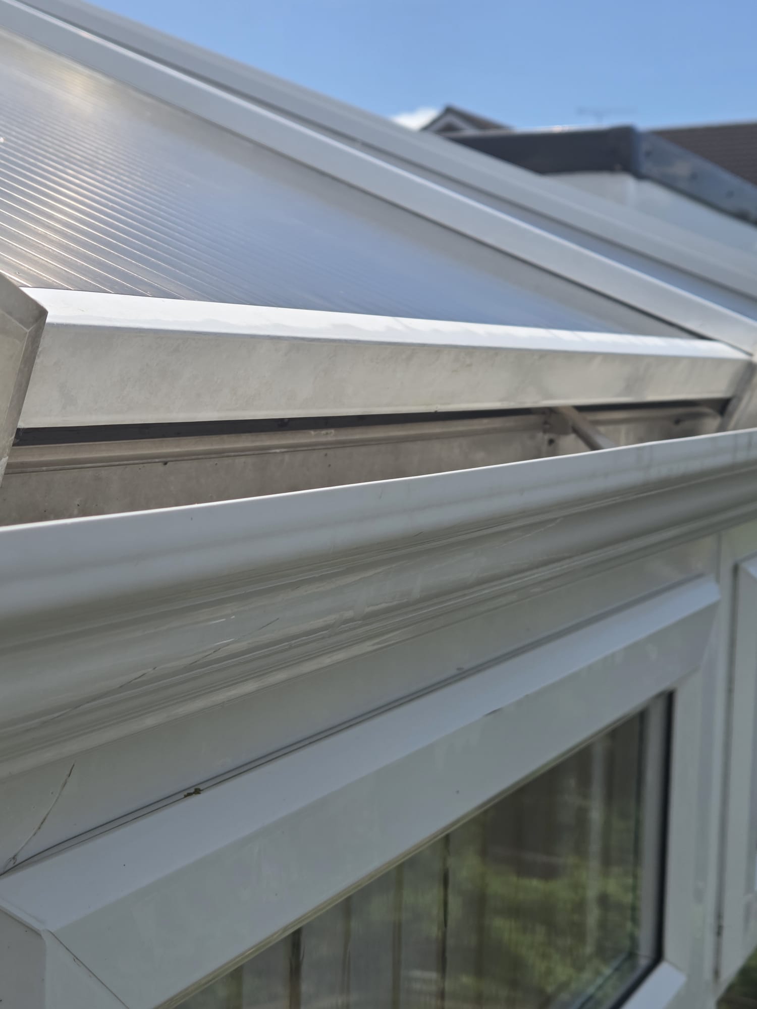 Close-up of conservatory roof edge showing algae and dirt build-up before cleaning